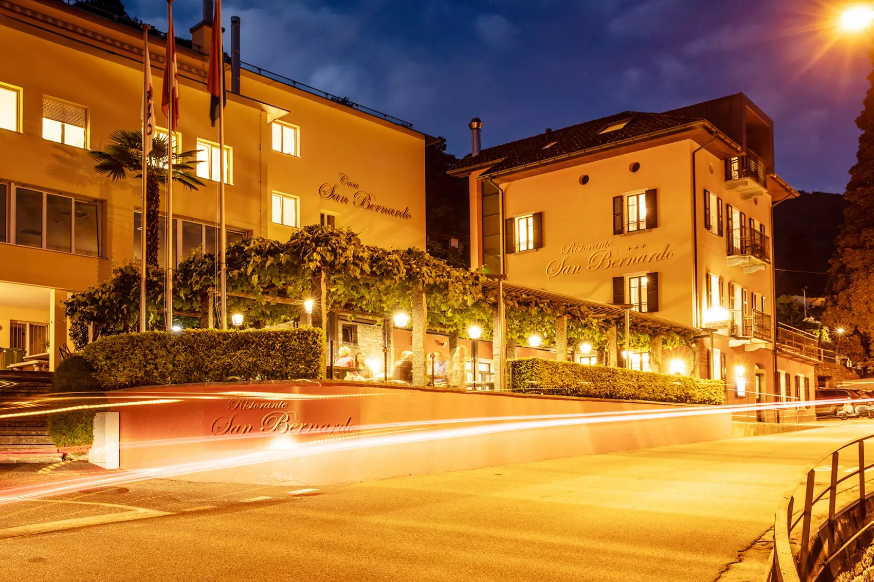 Beleuchtetes Gebaeude am Abend mit Aussenbereich und Restaurantbetrieb